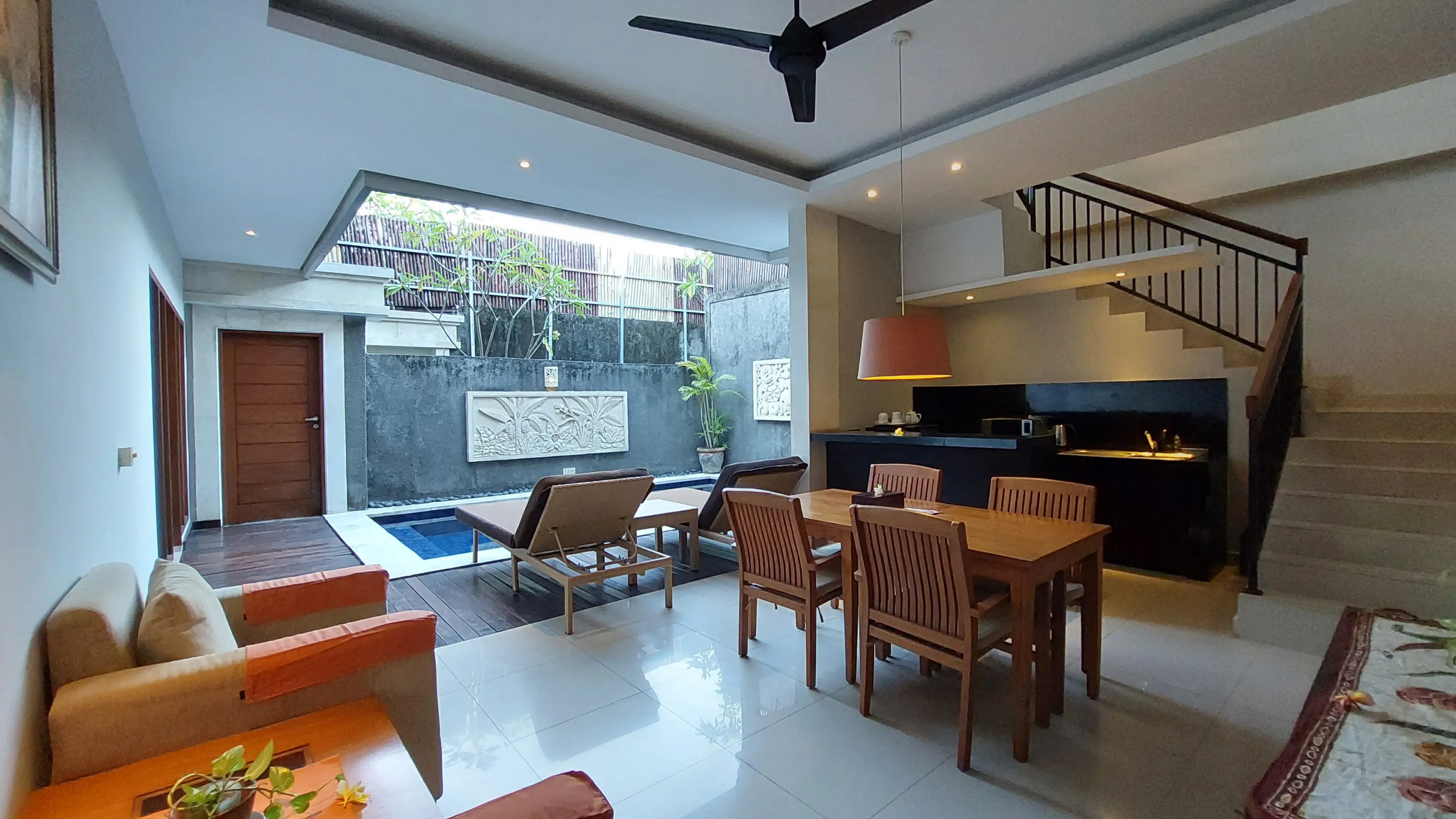 Open-plan ground floor of the two-bedroom villa with dining table, sun loungers, plunge pool and staircase to the second floor.