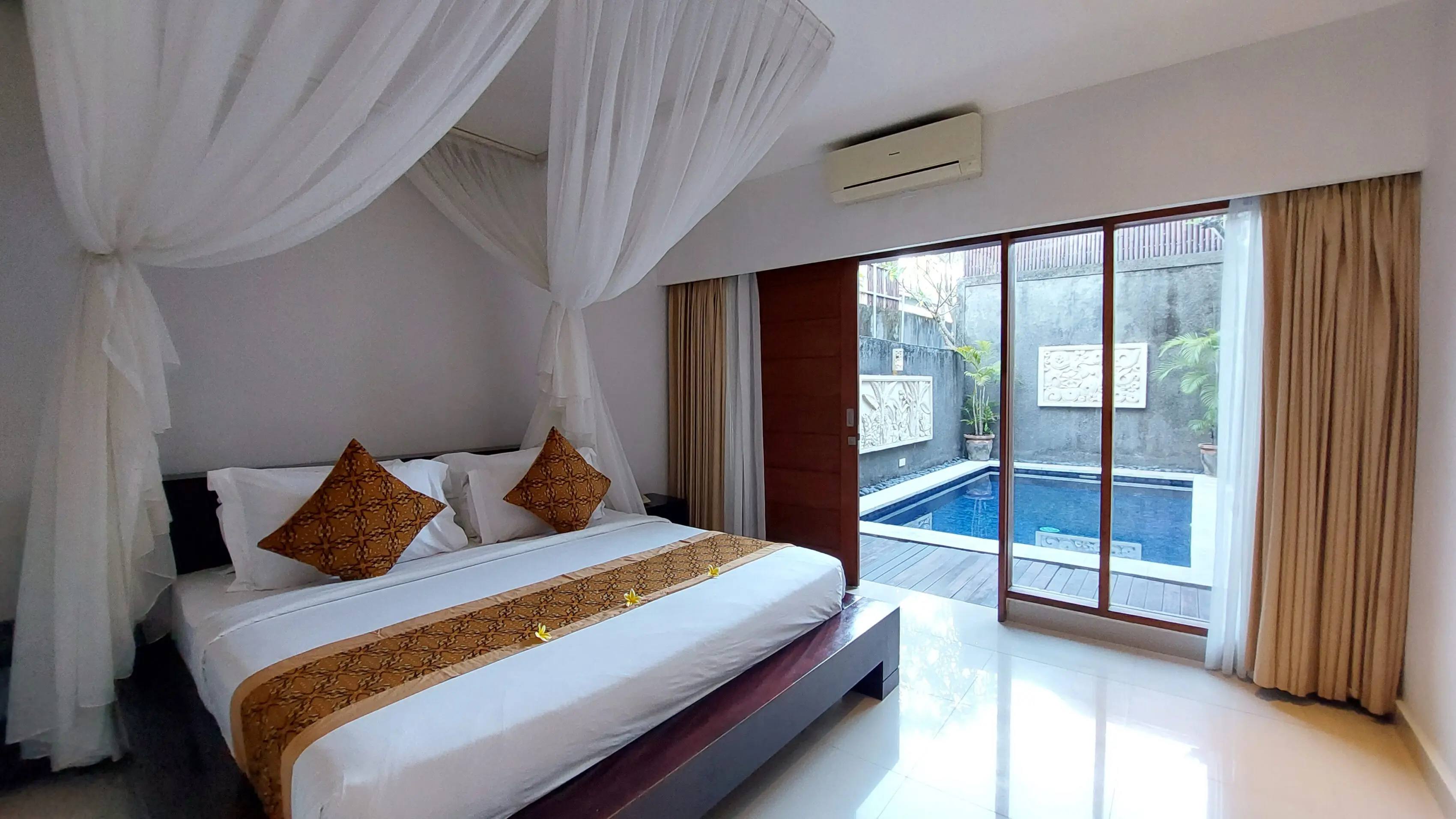 Luxury villa in Seminyak with canopy bed and private pool view through sliding glass doors at The Light Exclusive Villas & Spa.