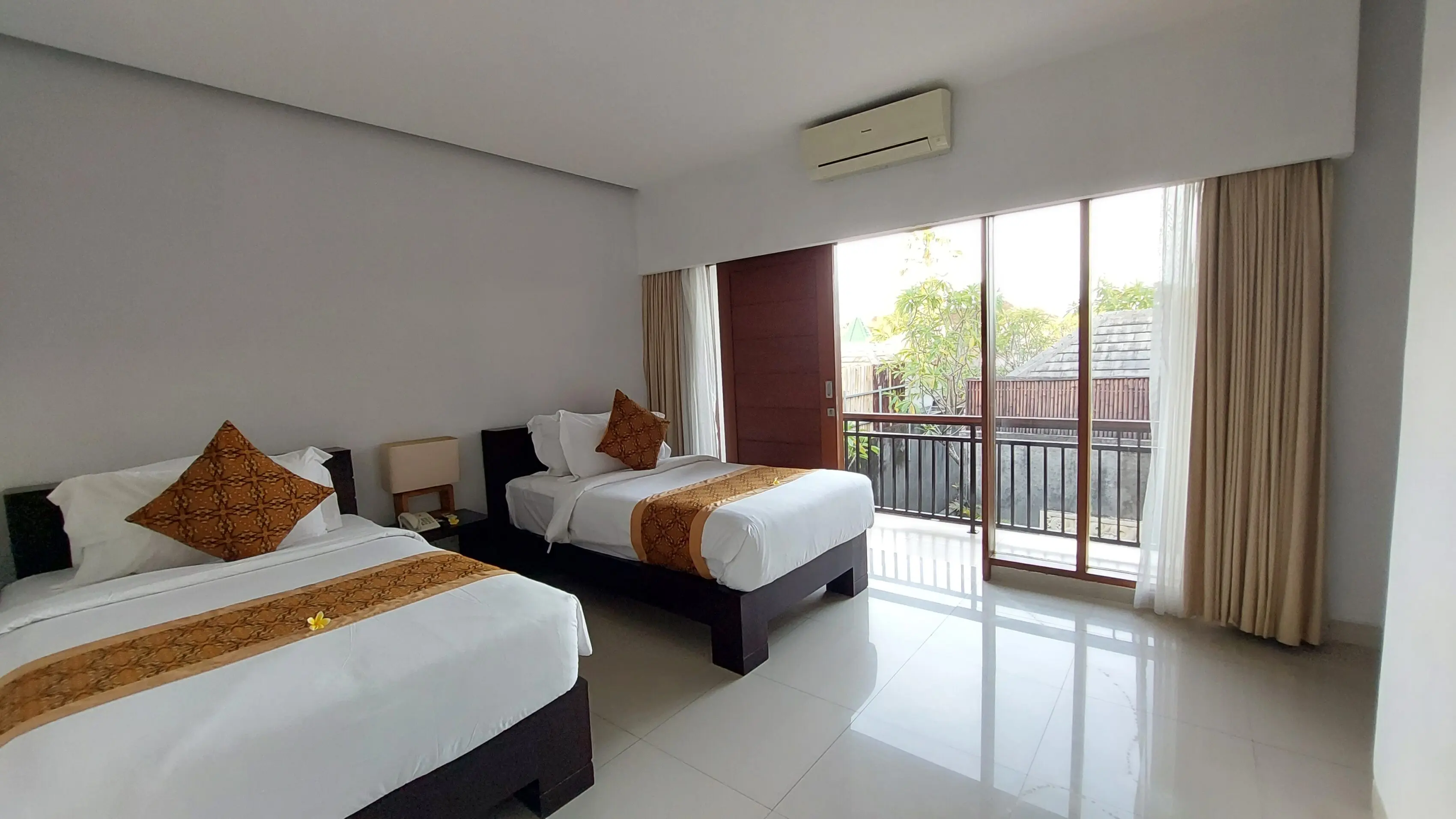 Two-bedroom villa with twin beds, elegant decor, sliding doors opening to garden views, at The Light Exclusive Villas & Spa, Seminyak.
