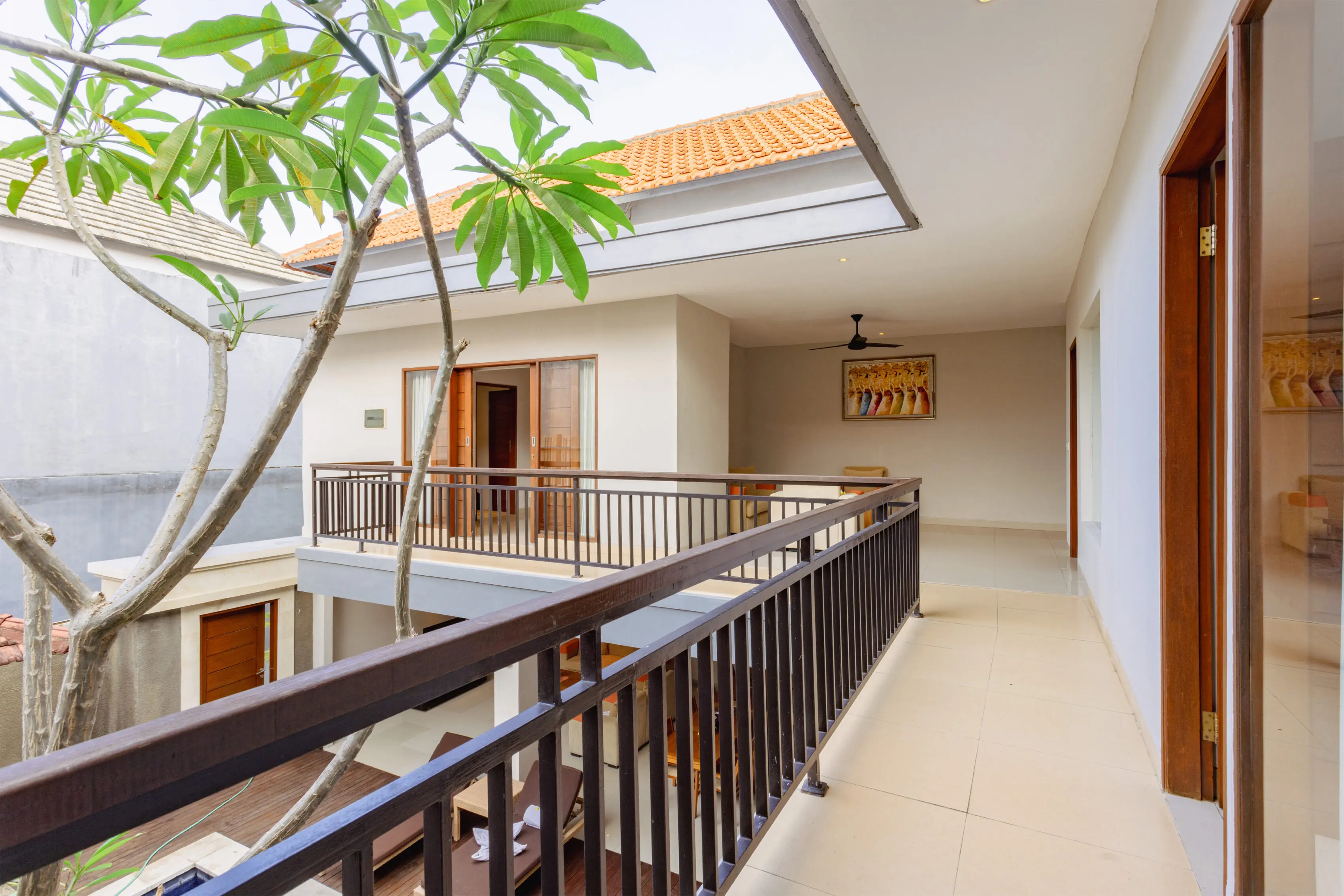 Open-plan villa dining area with a long wooden table for eight, pendant light, sofa lounge and view of the private pool.