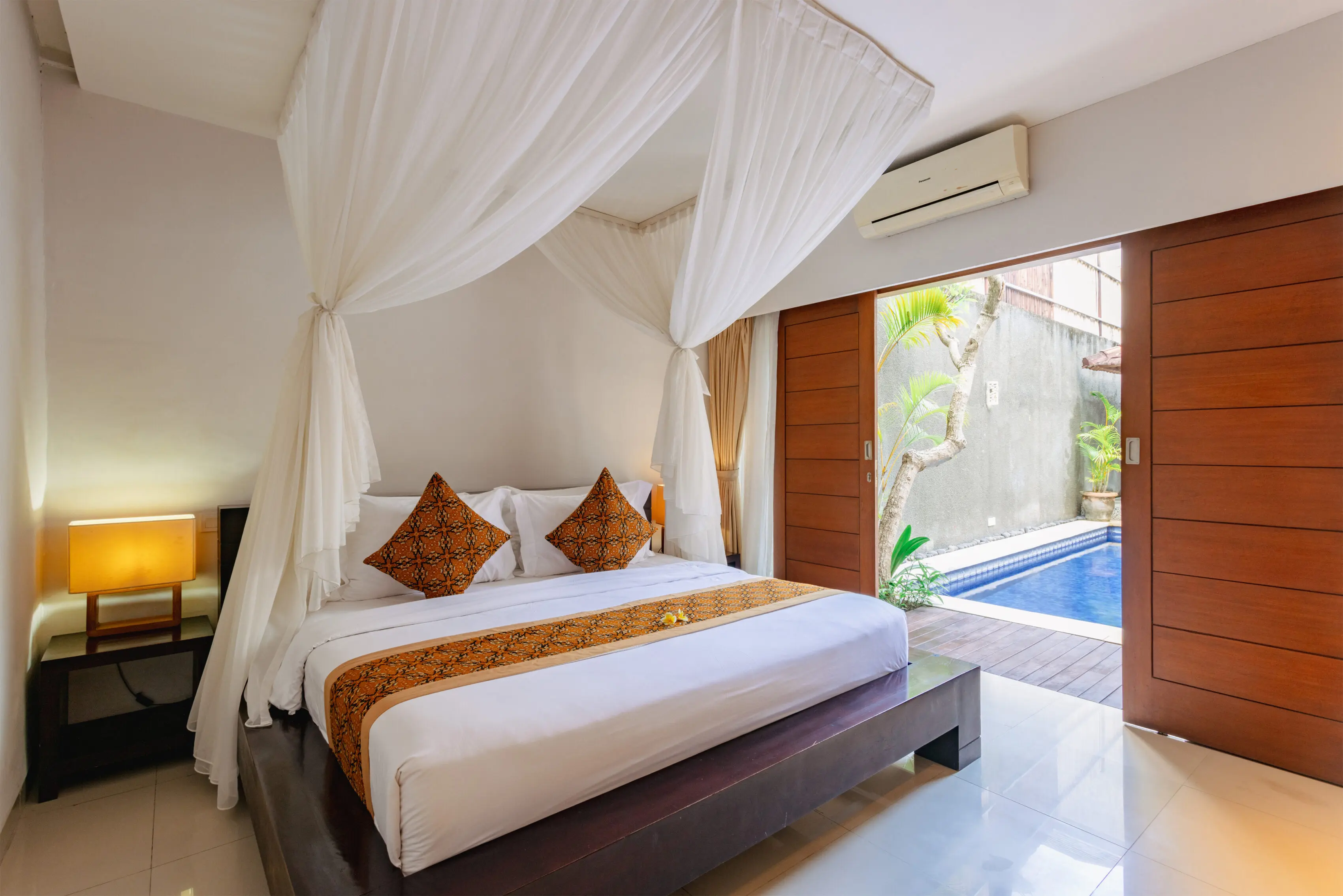 Spacious tiled bathroom with a freestanding oval bathtub, glass-enclosed rain shower and warm sandstone walls.