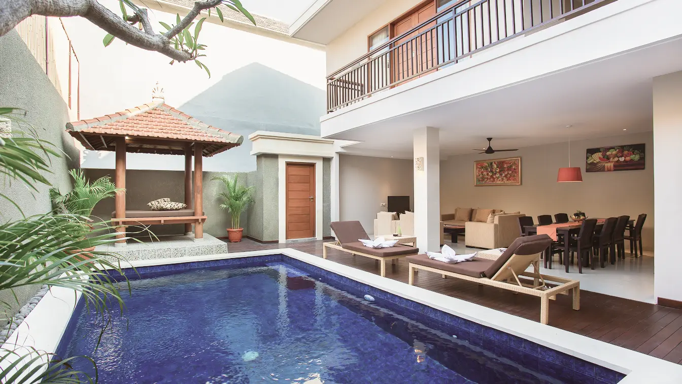 Spacious four-bedroom villa with a large blue private pool, twin sun loungers, Balinese bale gazebo and an open dining and living pavilion.