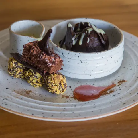 Decadent chocolate dessert with sauce and truffle presentation at The Light Exclusive Villas & Spa's tropical dining experience.