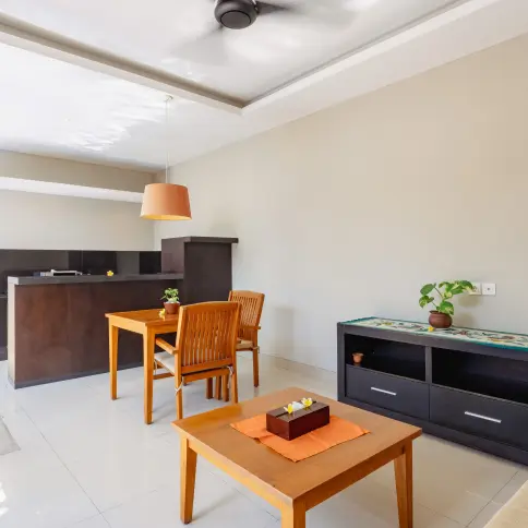 Dining area with wooden table and chairs, modern décor, pendant lighting, and a potted plant in a luxury Seminyak villa.