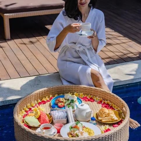 Floating breakfast by the pool at The Light Exclusive Villas & Spa, featuring tropical fruit, tea, and pastries.