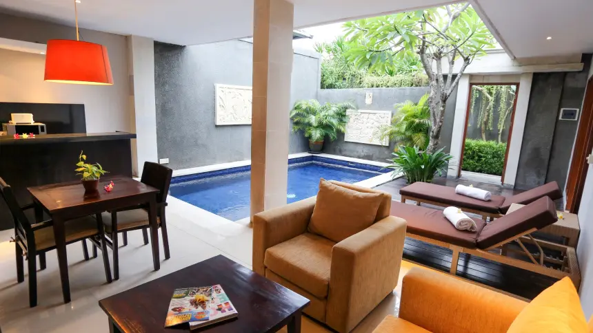 Villa lounge area with orange pendant light, dining table, two sun loungers and private pool behind.