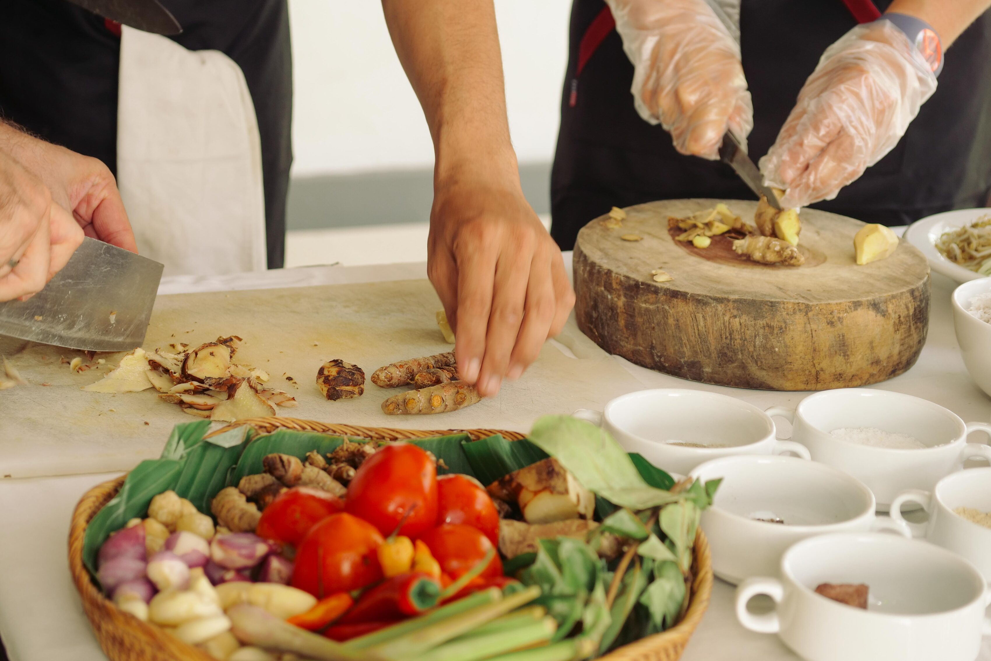 Hands preparing ingredients for a Balinese cooking with fresh vegetables and spices at The Light Exclusive Villas & Spa.