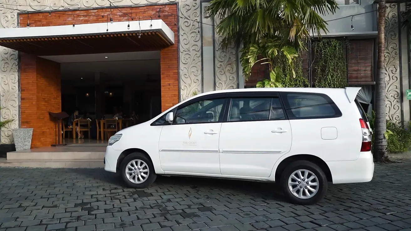 White van parked outside The Light Exclusive Villas & Spa entrance in Seminyak, Bali, with elegant facade in background.