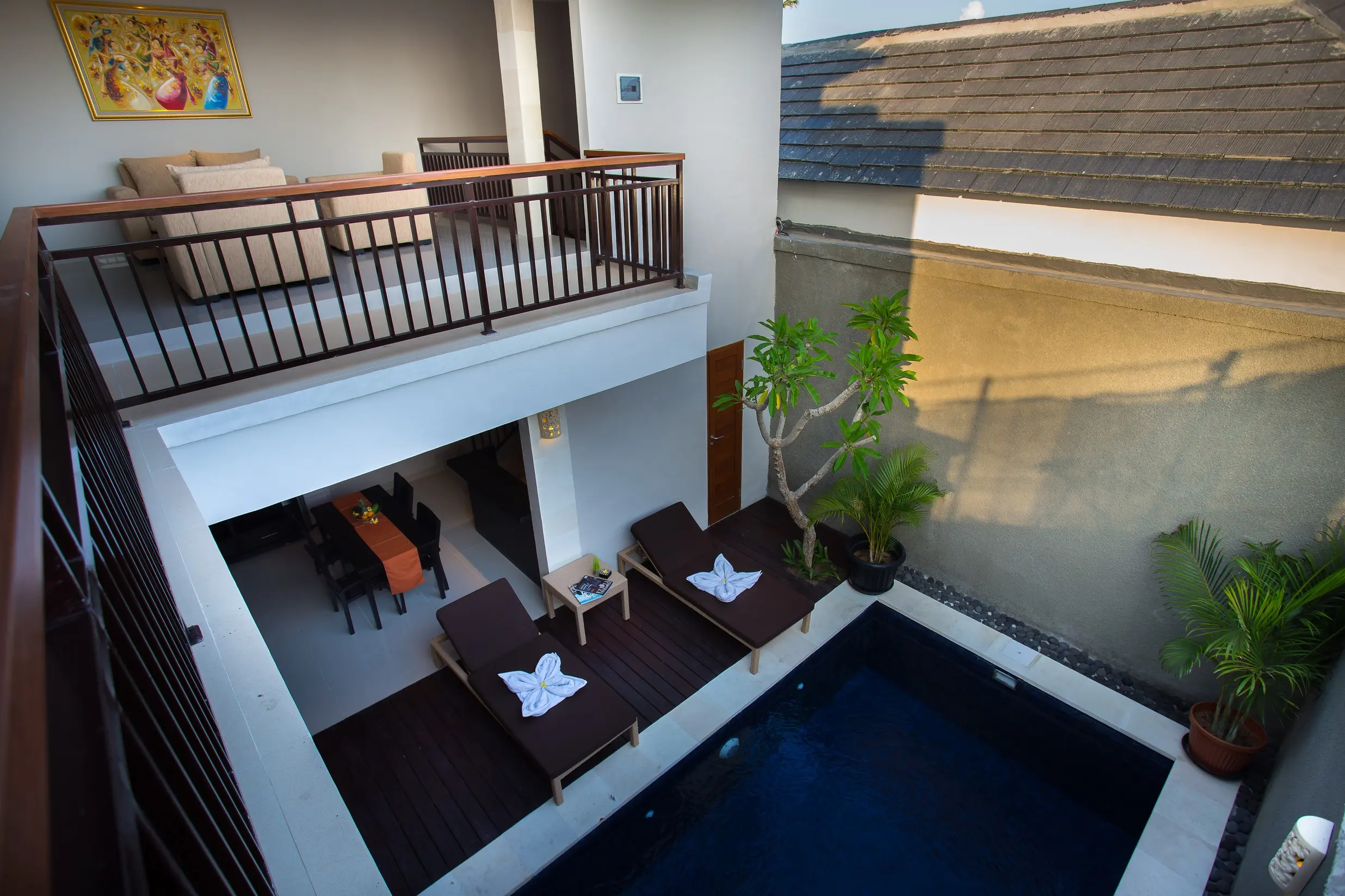 Top-down view of a two-bedroom villa courtyard with private pool, sun loungers, upper-floor balcony and lounge area.