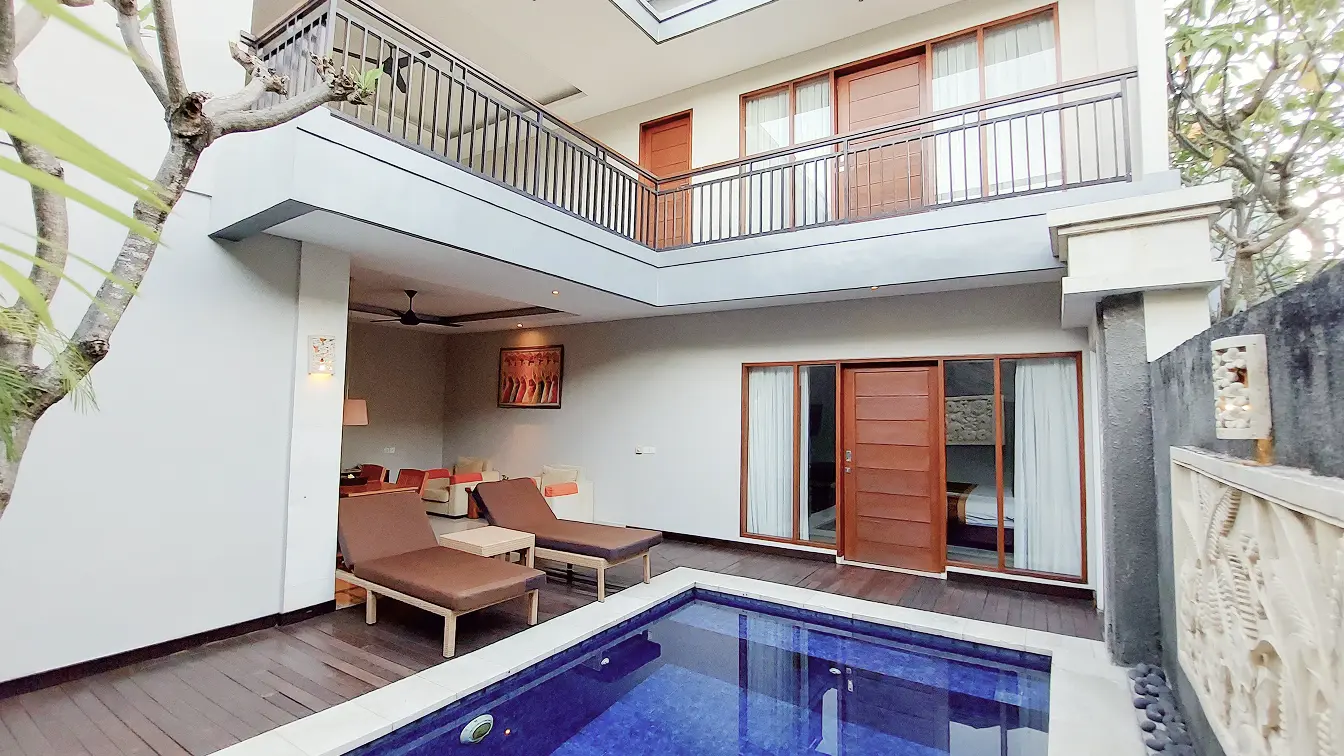 Two-bedroom villa courtyard with private pool, twin sun loungers and a two-storey balcony overlooking the deck.