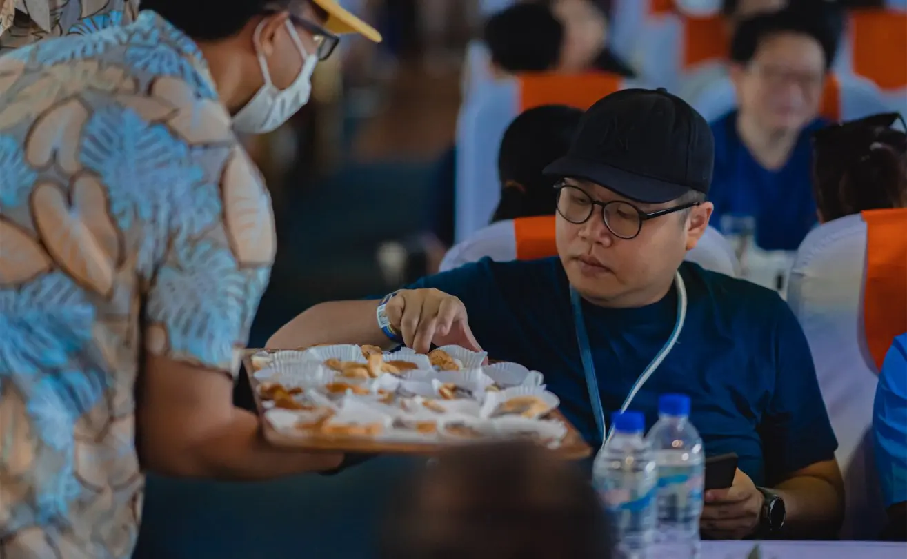 Guest selecting pastries from a tray on a lively dinner cruise, highlighting vibrant leisure experiences.