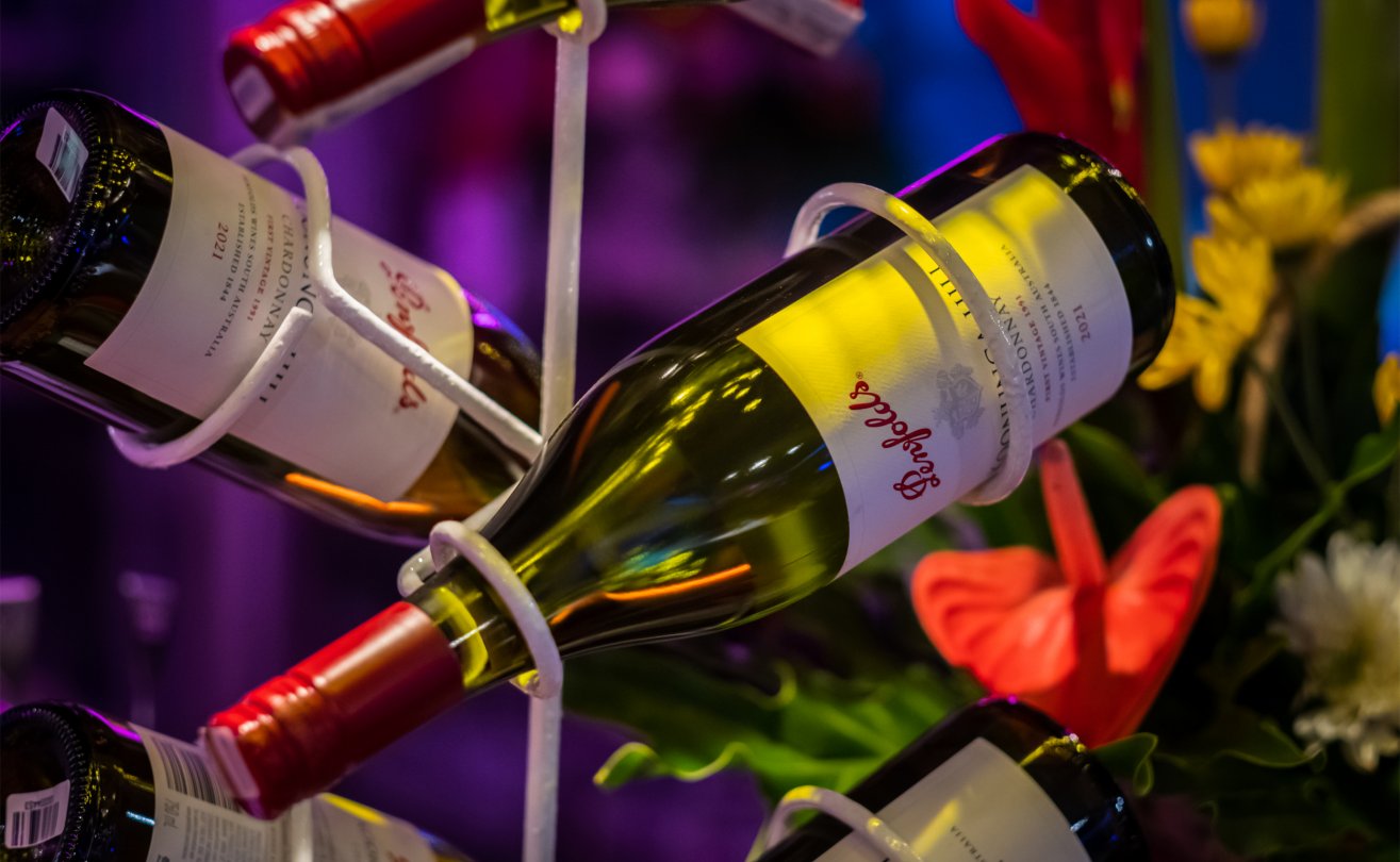 Wine bottles elegantly displayed with vibrant flowers in a cozy setting at The Light Exclusive Villas & Spa in Seminyak.