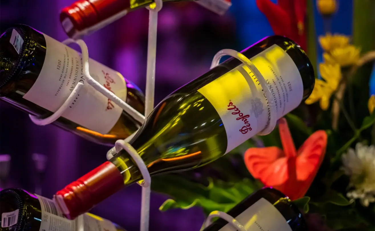 Wine bottles elegantly displayed with vibrant flowers in a cozy setting at The Light Exclusive Villas & Spa in Seminyak.